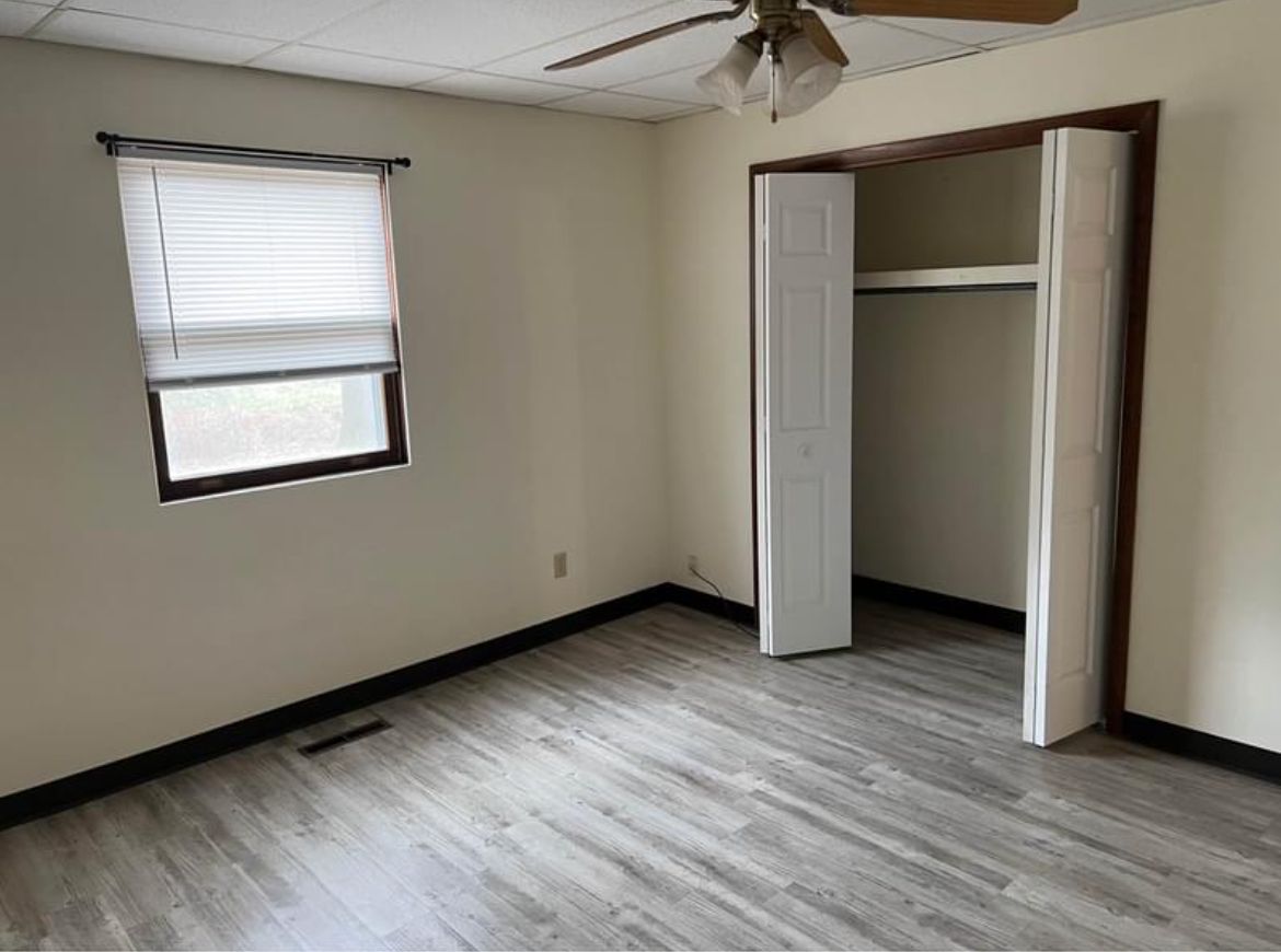 An empty bedroom with hardwood floors and a ceiling fan.