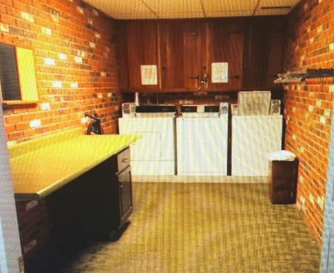 A laundry room with two washers and two dryers