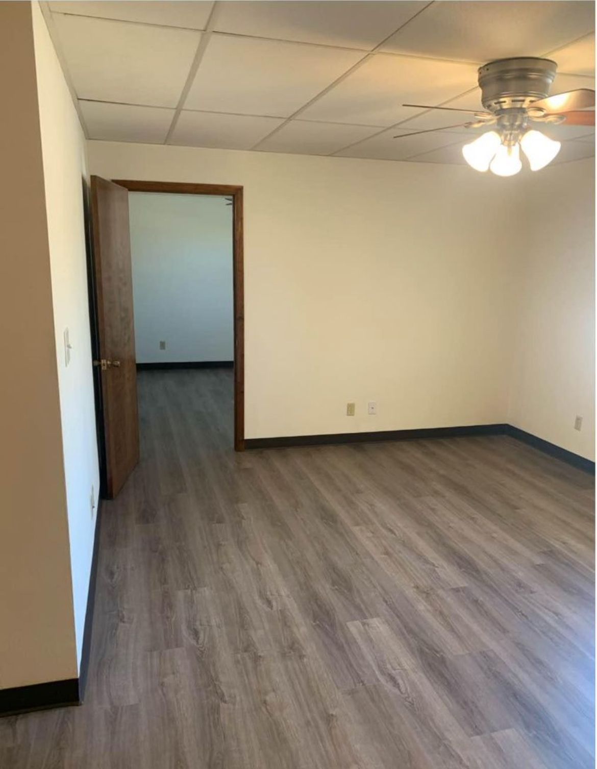 An empty room with hardwood floors and a ceiling fan.