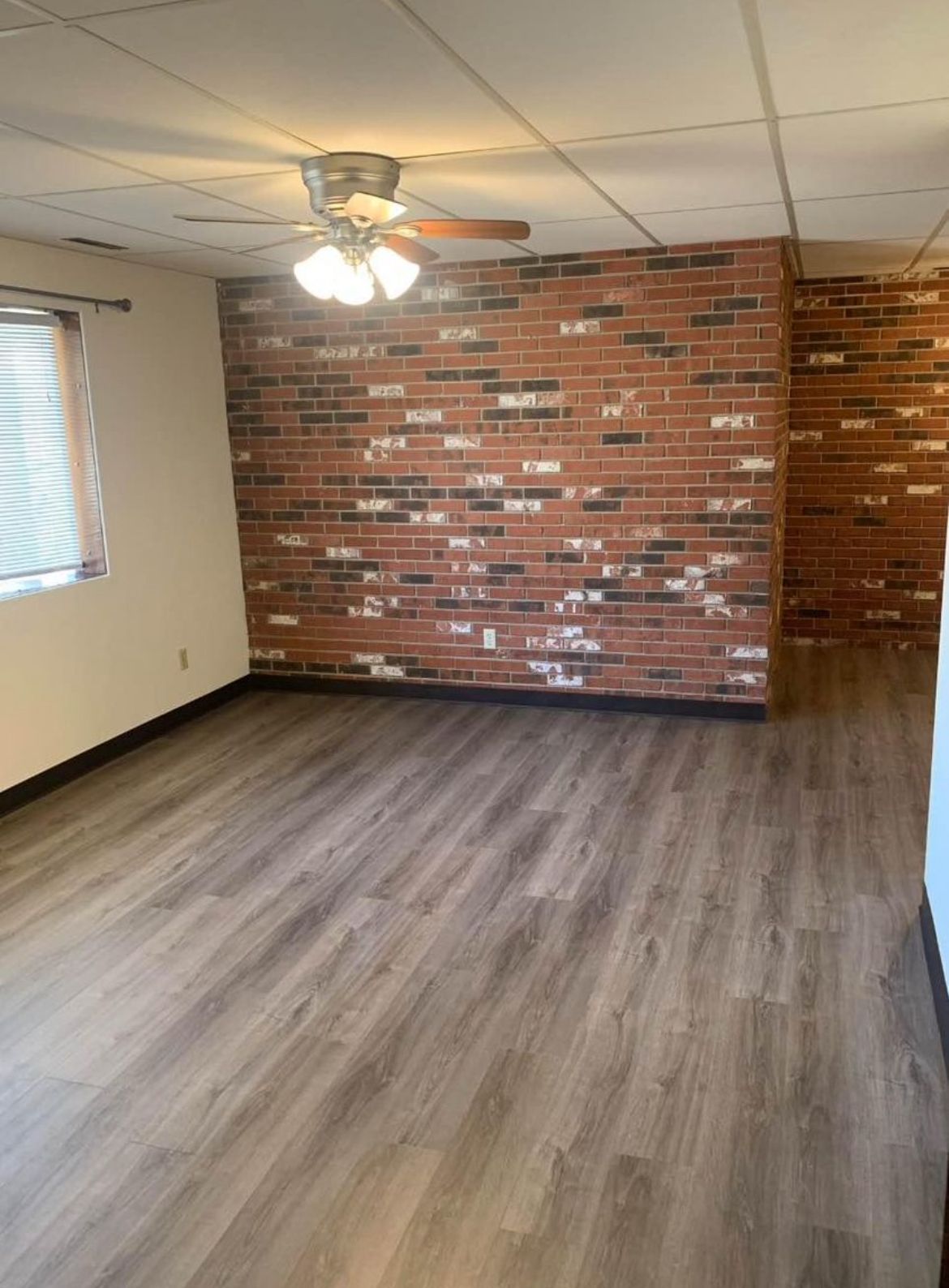 A living room with a brick wall and a ceiling fan.