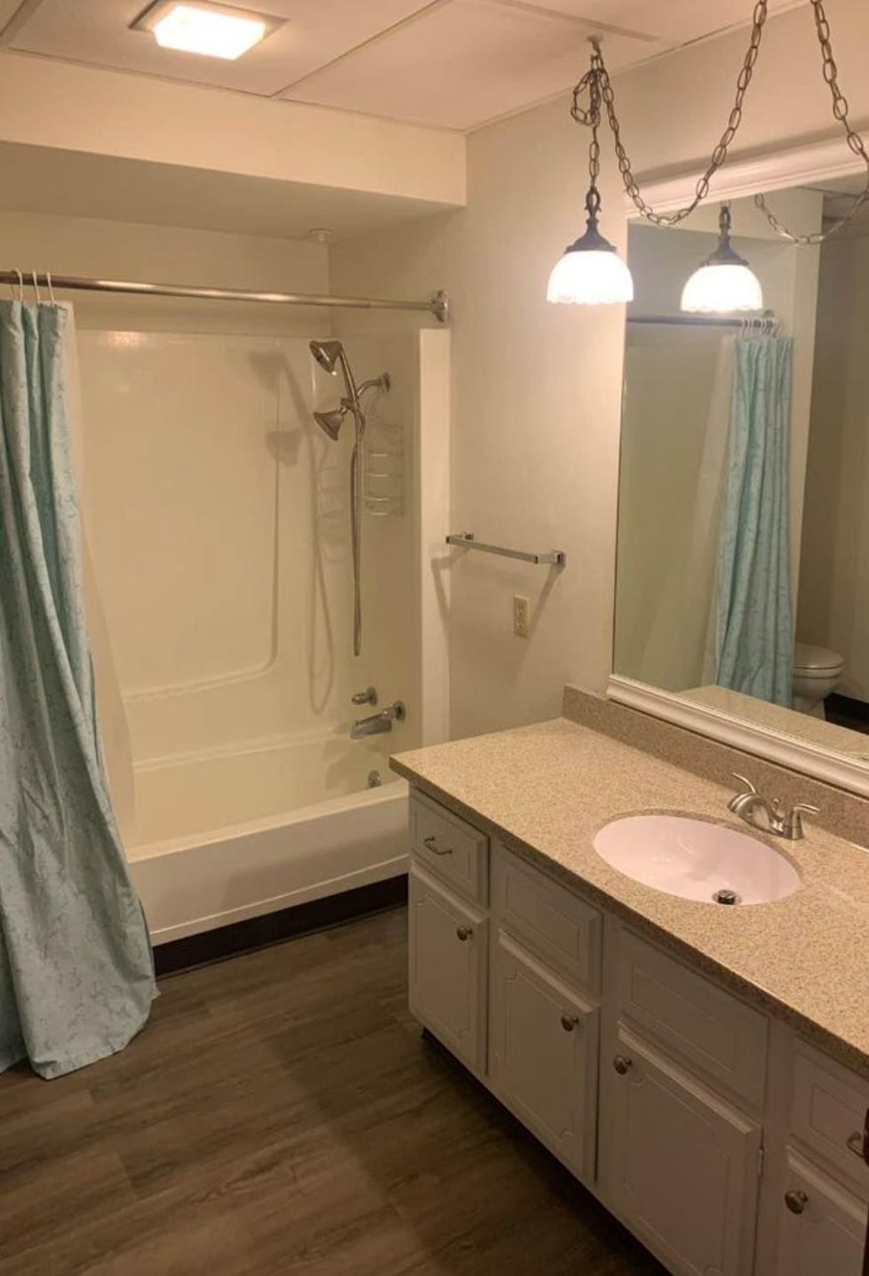 A bathroom with a sink , tub , shower and mirror.