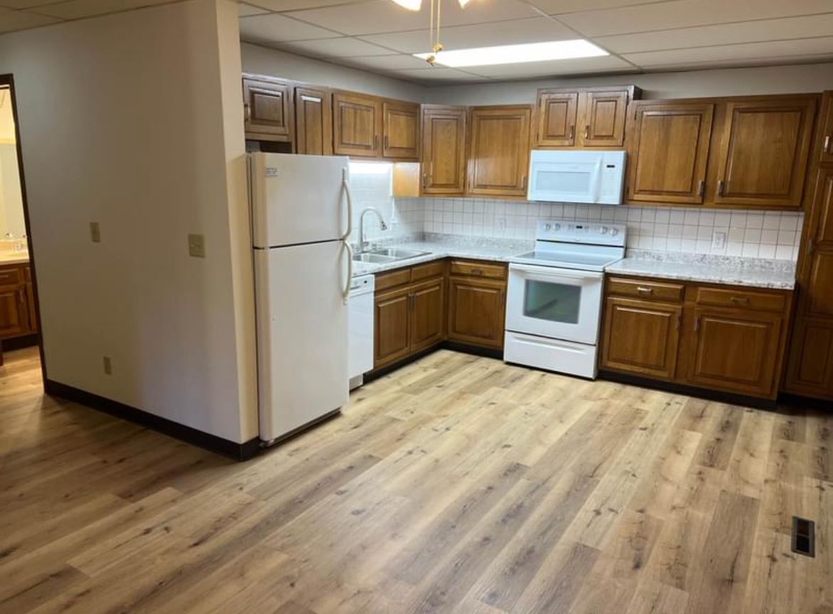 A kitchen with wooden cabinets , a refrigerator , a stove , and a microwave.
