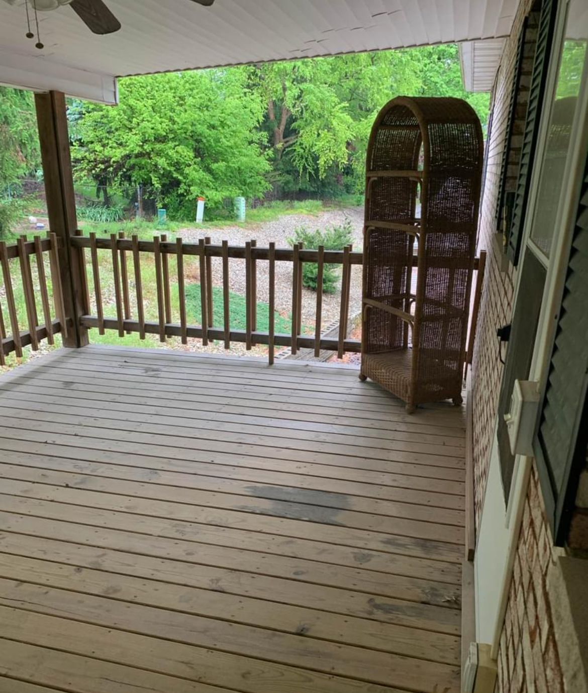 A porch with a wooden fence and a ceiling fan.