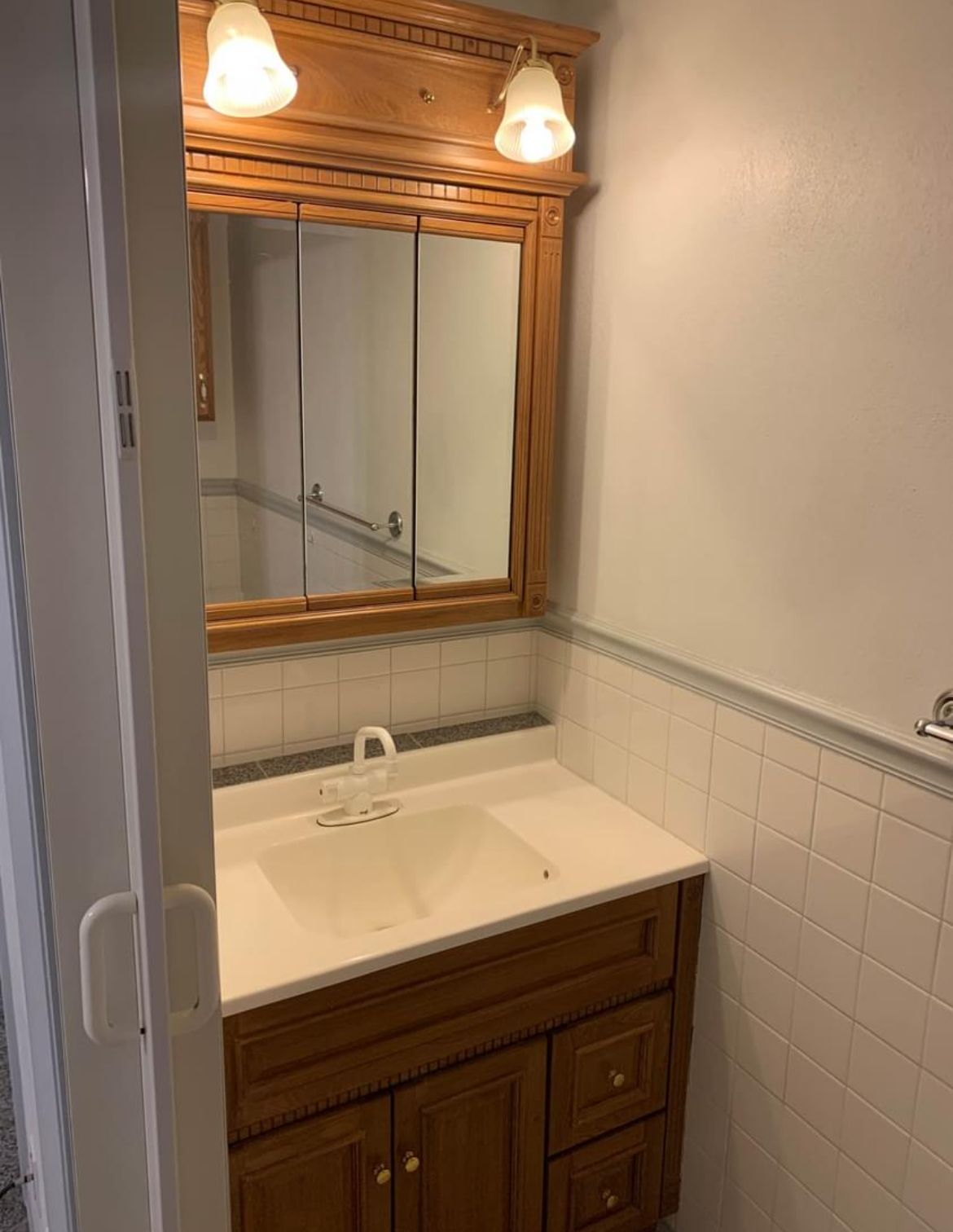 A bathroom with a sink , mirror and light fixtures.