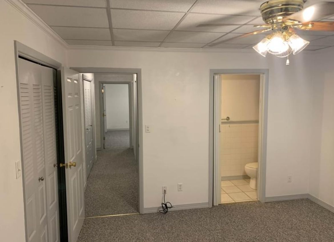 An empty room with a ceiling fan and a toilet.