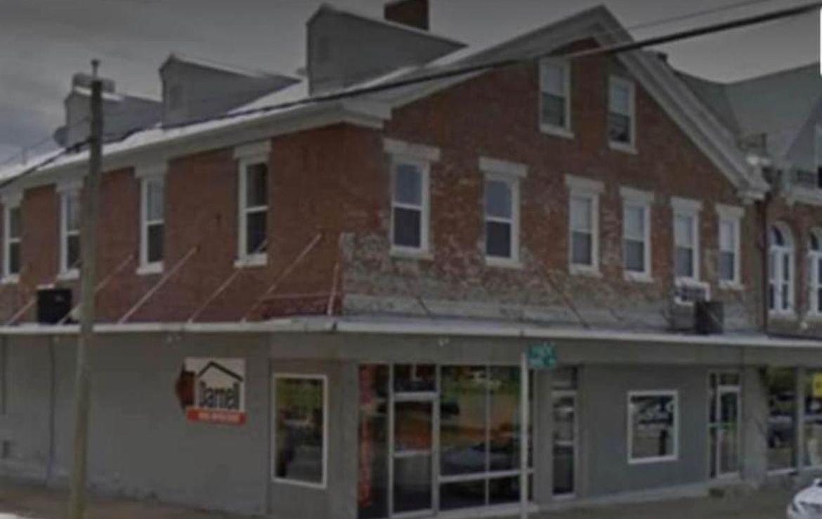A large brick building with a lot of windows is on the corner of a street.