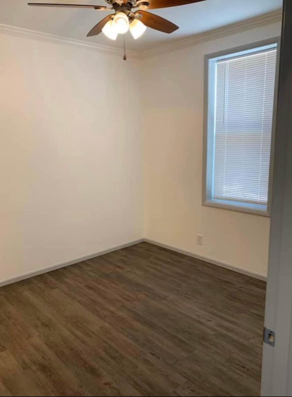 An empty room with a ceiling fan and a window.
