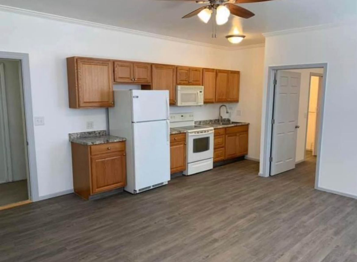 A kitchen with a refrigerator , stove , microwave , sink and ceiling fan.