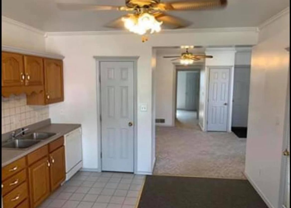 A kitchen with wooden cabinets and a ceiling fan