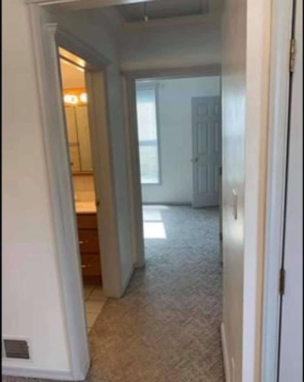 A hallway leading to a bathroom and a bedroom in a house.