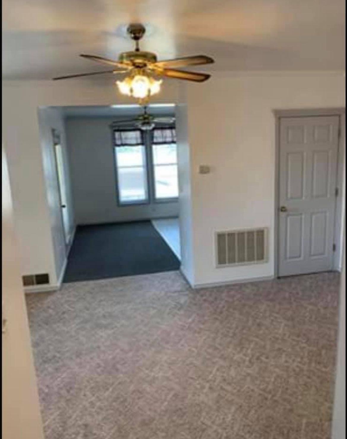 A living room with a ceiling fan and a door.