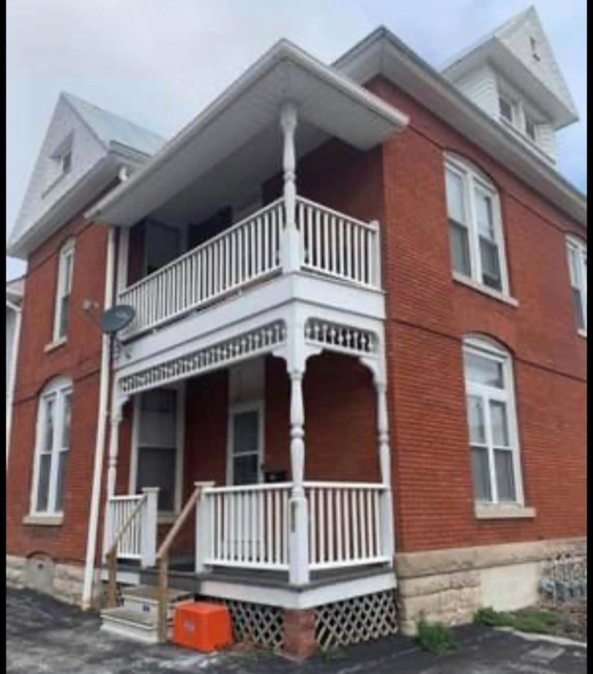 A red brick house with a white porch and stairs