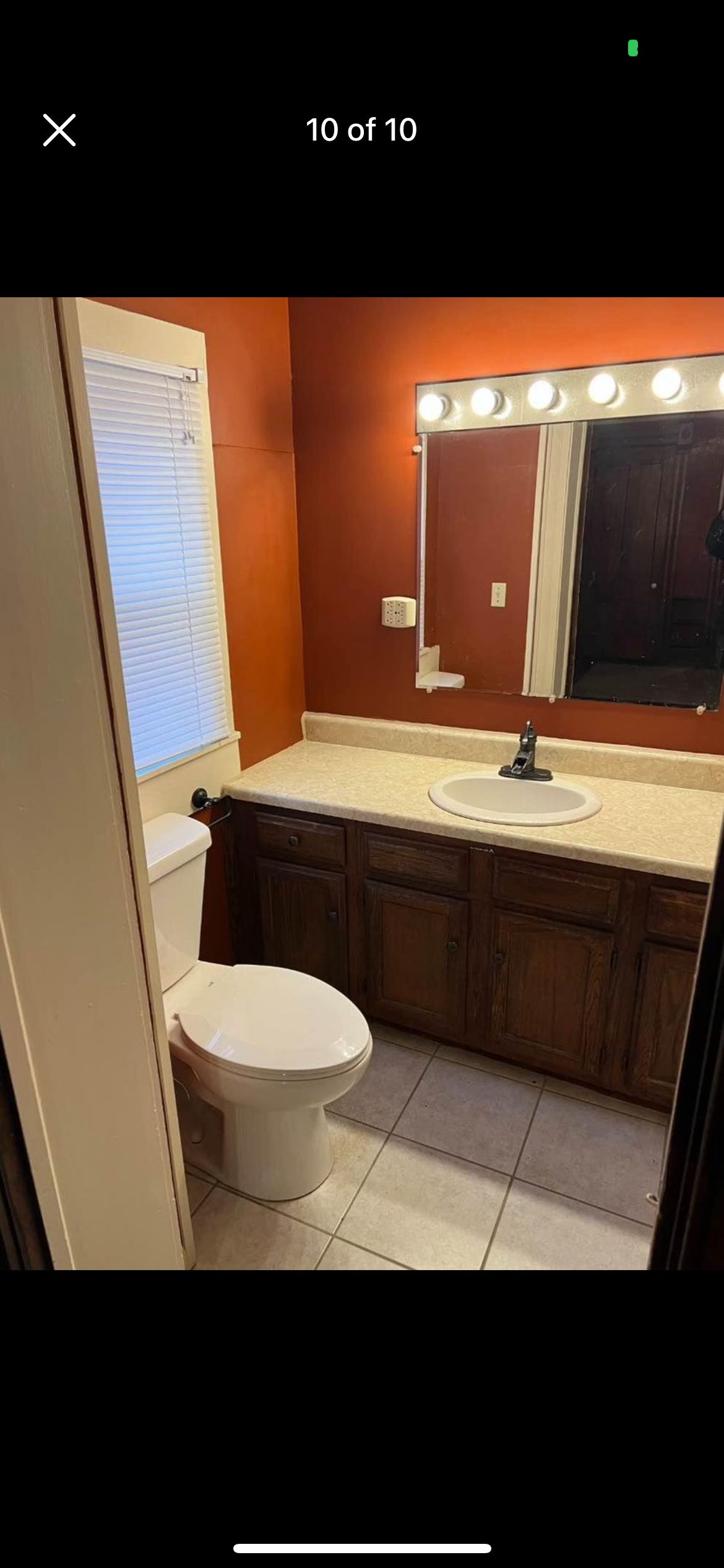 A bathroom with a toilet , sink and mirror.