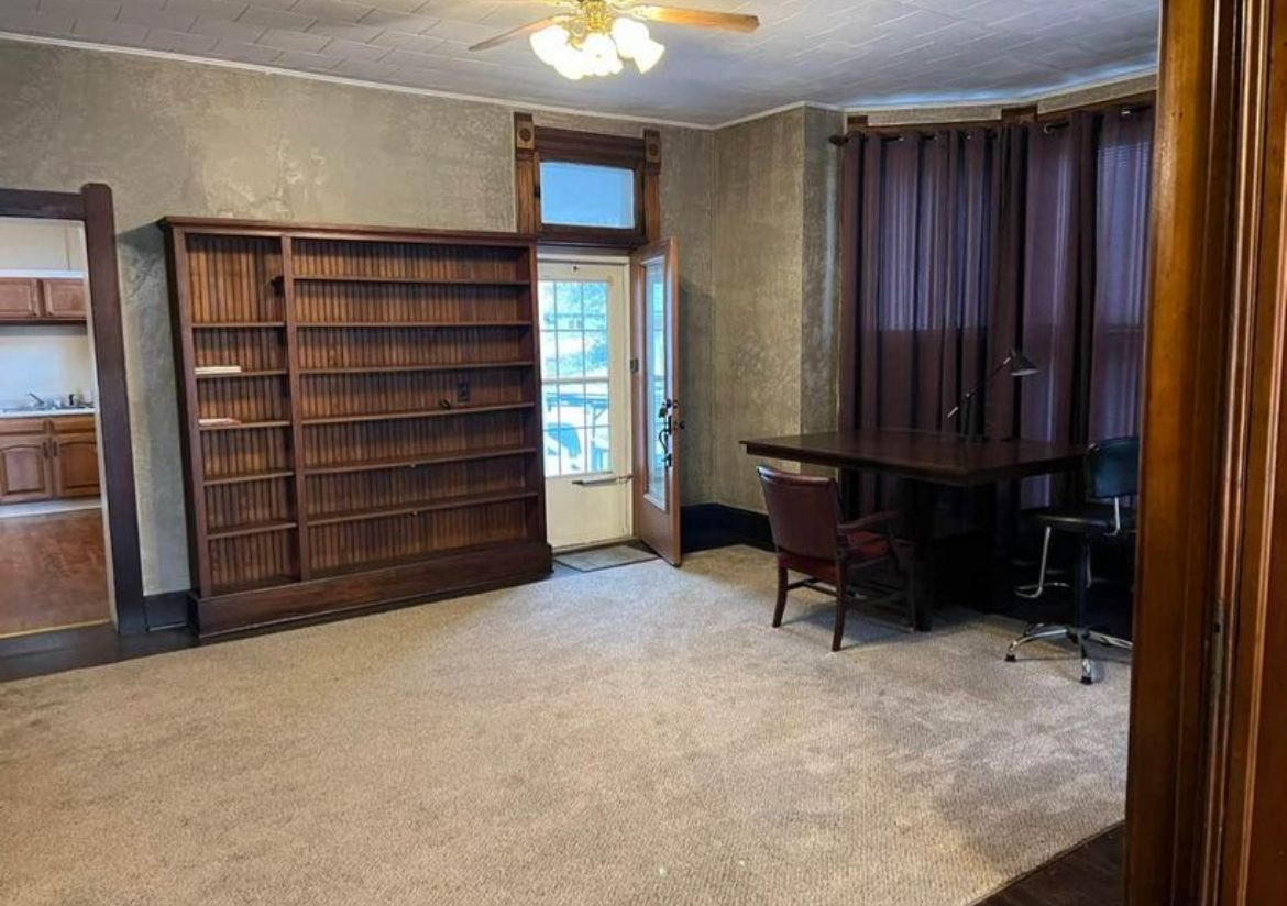 An empty room with a desk , chair and shelves.