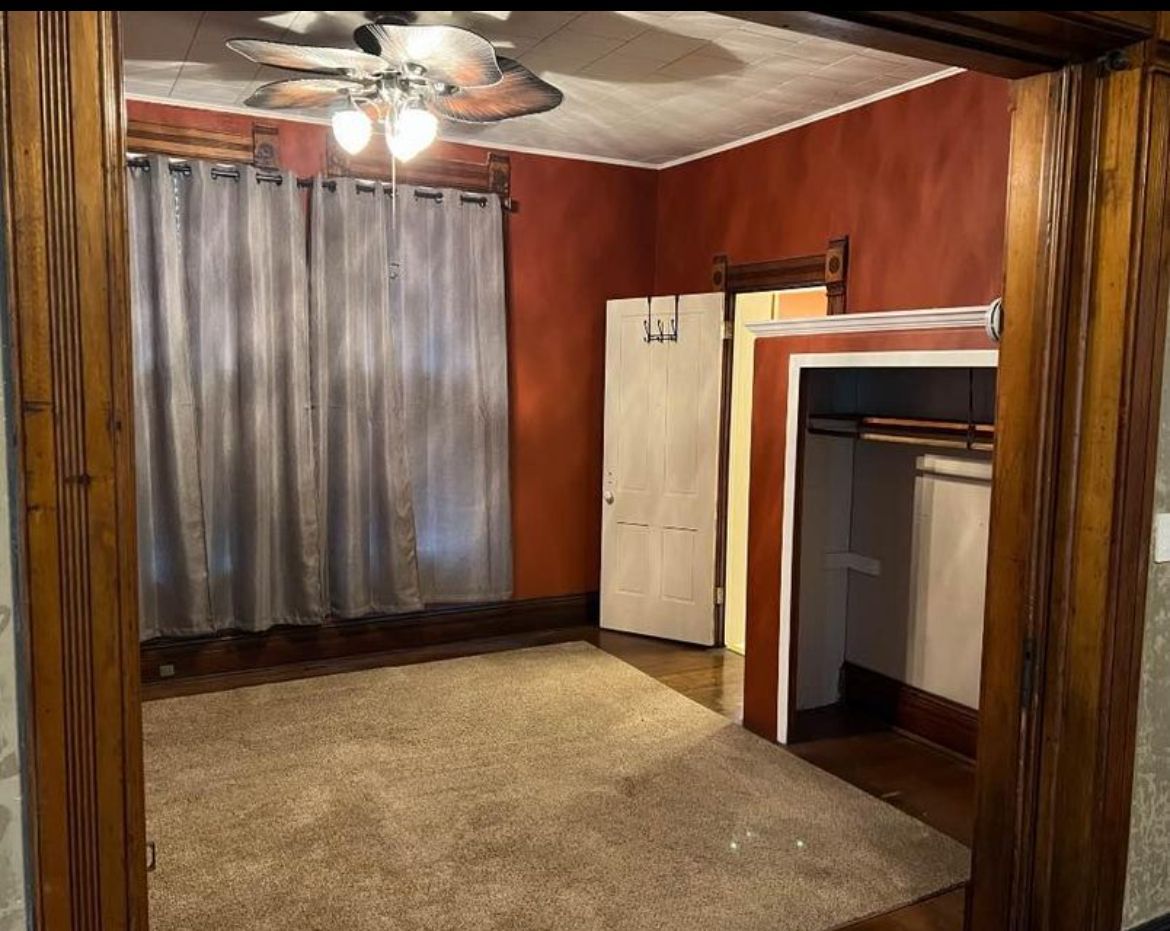 An empty room with a ceiling fan and a closet.