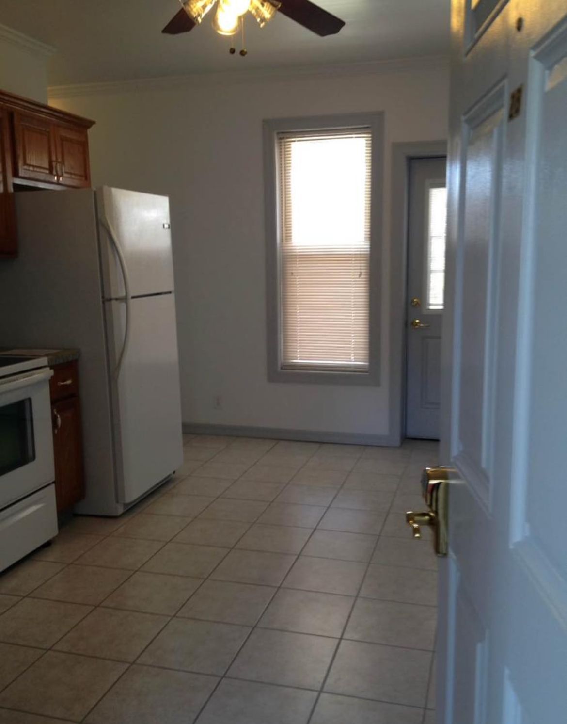A kitchen with a refrigerator , stove , and ceiling fan.