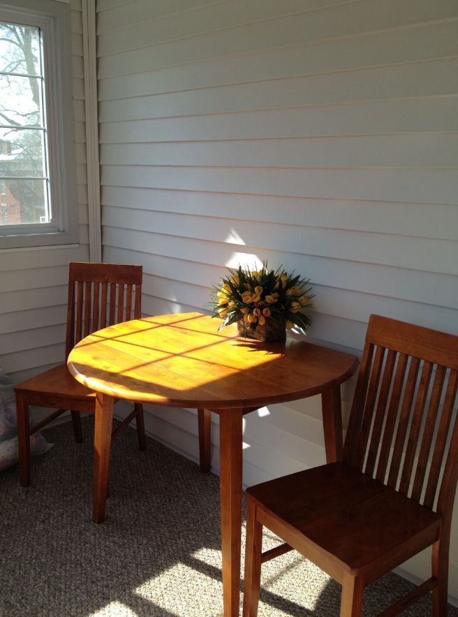 A table with two chairs and a vase of flowers on it