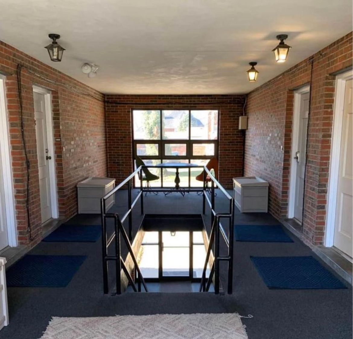A hallway with brick walls and white doors and stairs