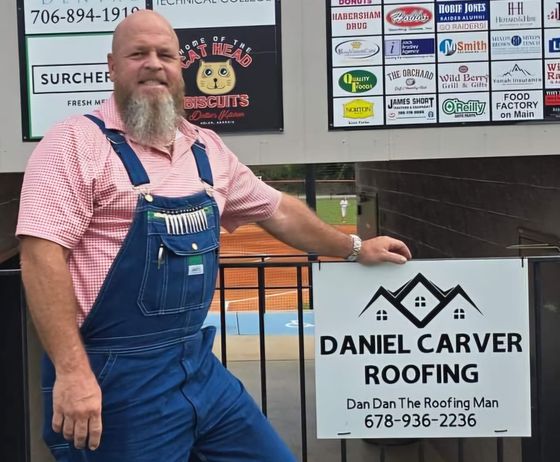 A man in overalls is standing next to a daniel carver roofing sign