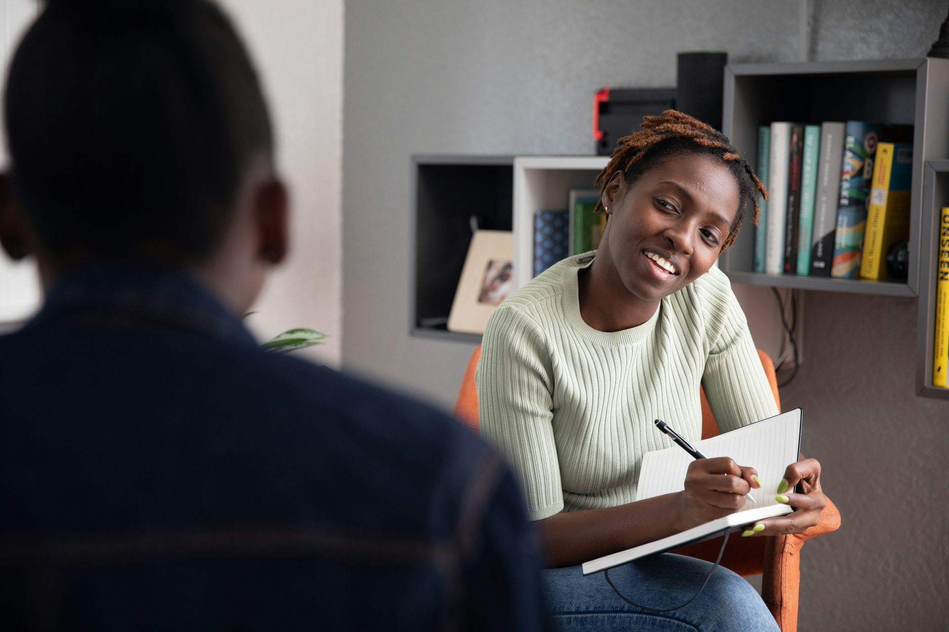 A female therapist taking notes during a therapy session with a client, representing trauma-informed care for childhood trauma survivors.