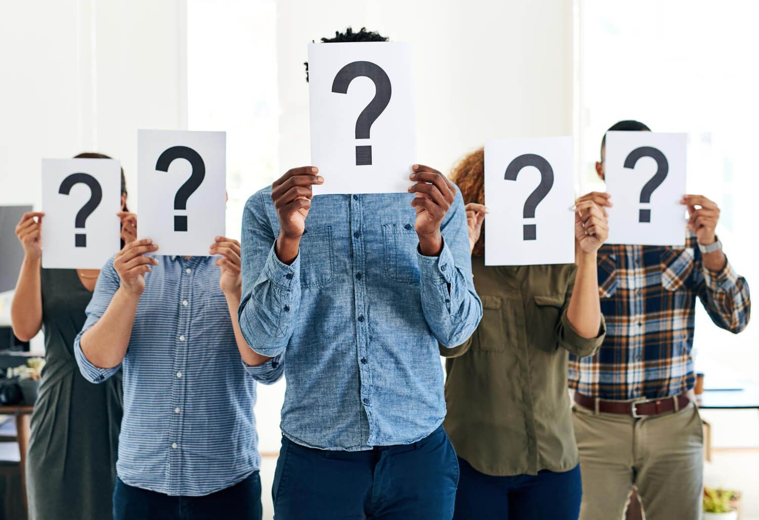 Group of people holding question mark signs representing frequently asked questions about Internal Family Systems therapy and trauma treatment