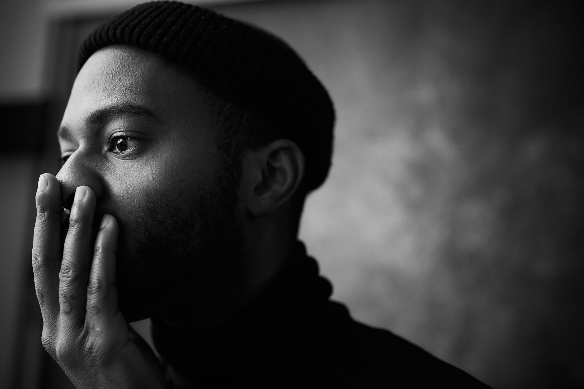 Black and white portrait of a thoughtful young man with his hand near his face, looking pensive and reflective, illustrating the mental state of being caught in common thinking traps.