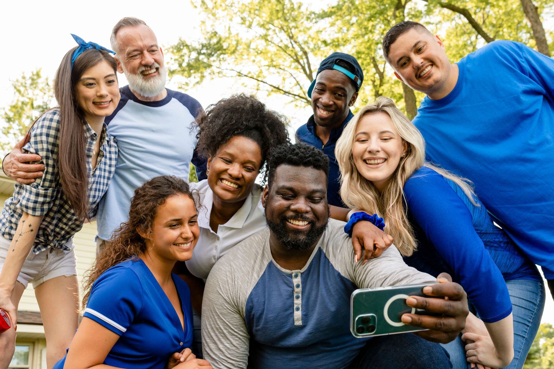 Diverse group of happy friends of different ages and ethnicities celebrating together outdoors, demonstrating healthy supportive relationships for trauma recovery