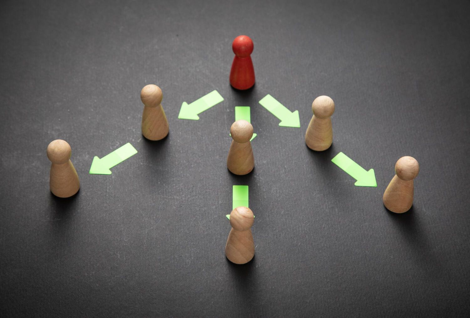 Red game piece in center with green arrows pointing to surrounding wooden pieces, illustrating therapeutic relationship and connection