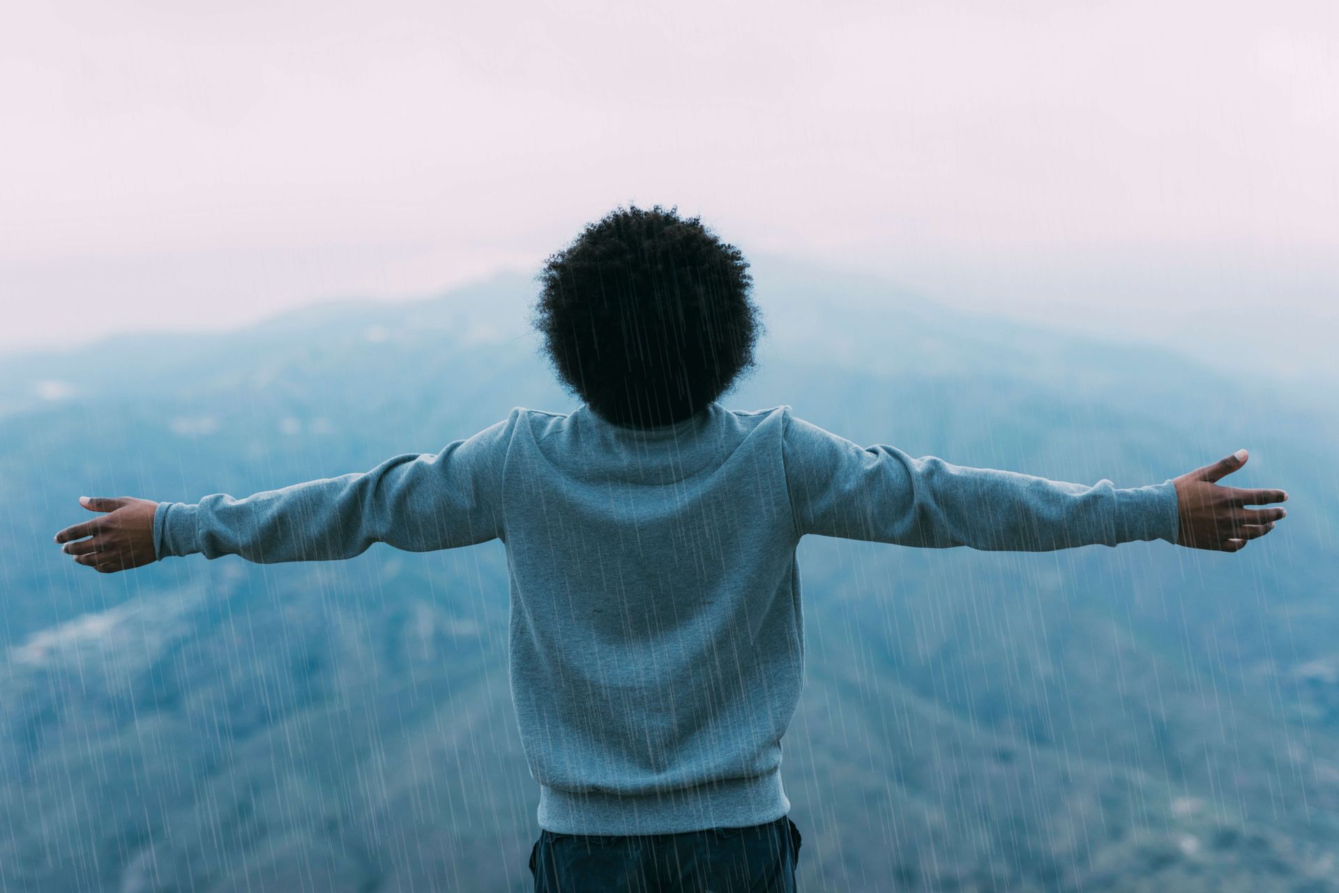 Person with arms outstretched facing mountain landscape symbolizing resilience and trauma recovery