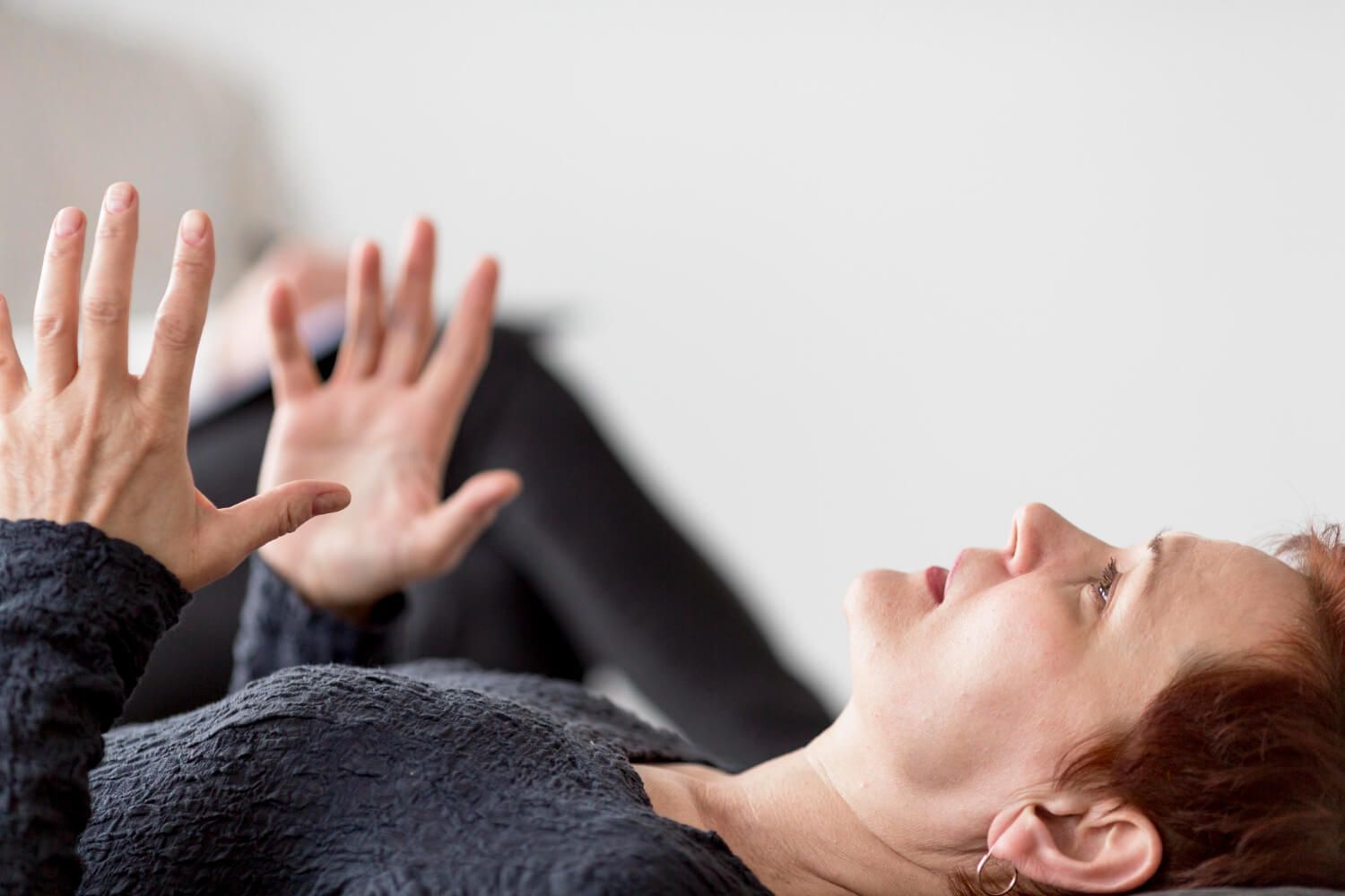 Person lying comfortably in therapy session with hands gently raised, demonstrating somatic experiencing techniques for trauma release