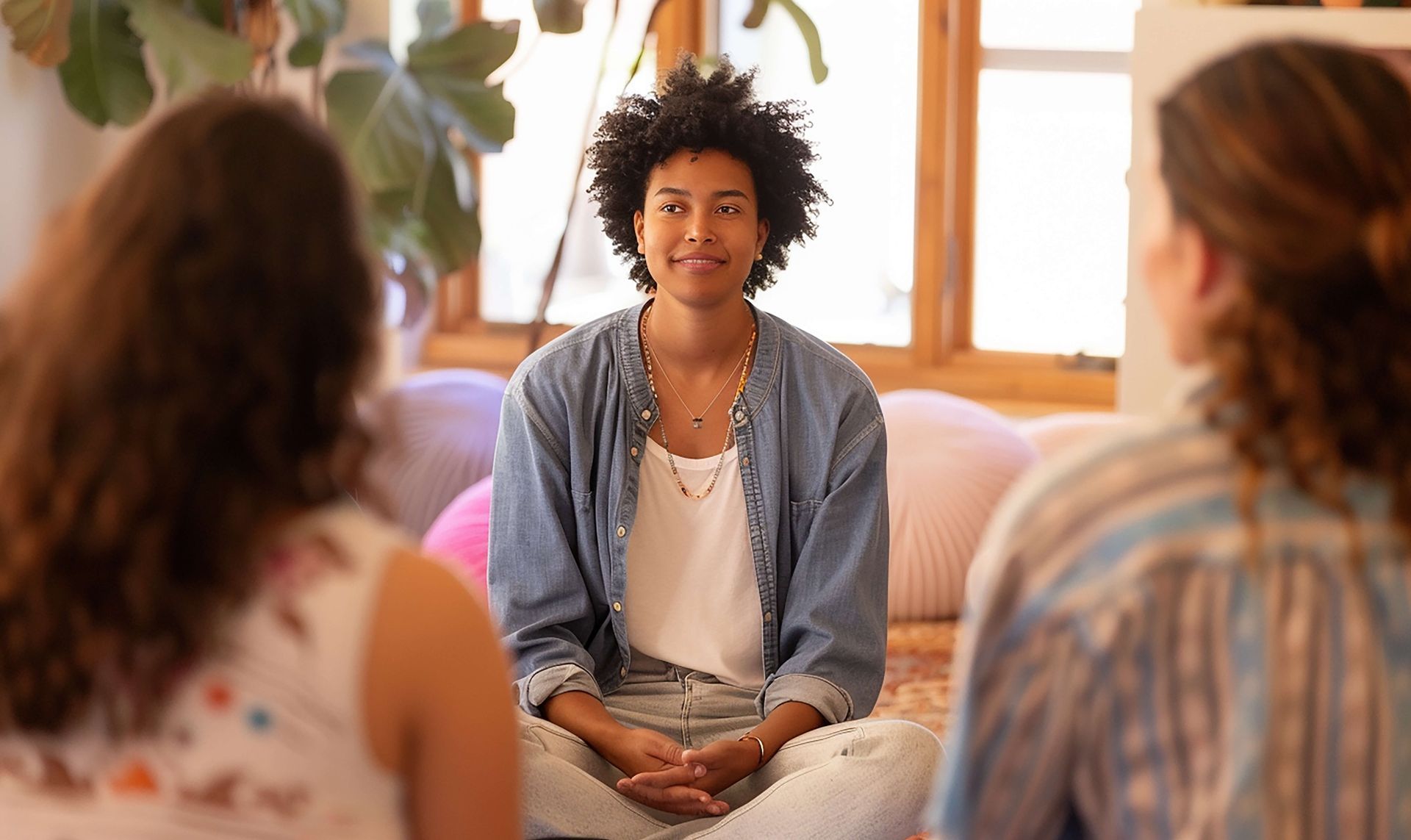 Professional therapy session with Black female therapist and two clients in comfortable office setting, showing trauma-informed care for rebuilding self-trust