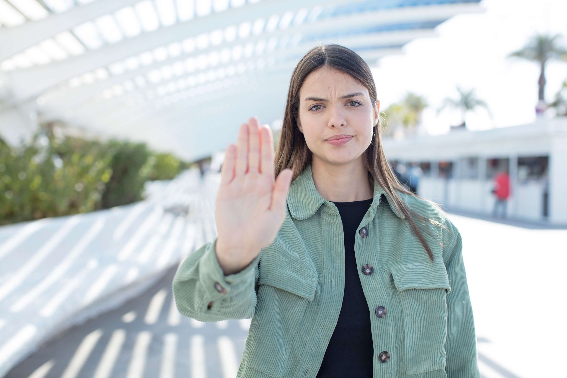 Woman in green jacket making stop gesture to demonstrate trauma trigger management technique