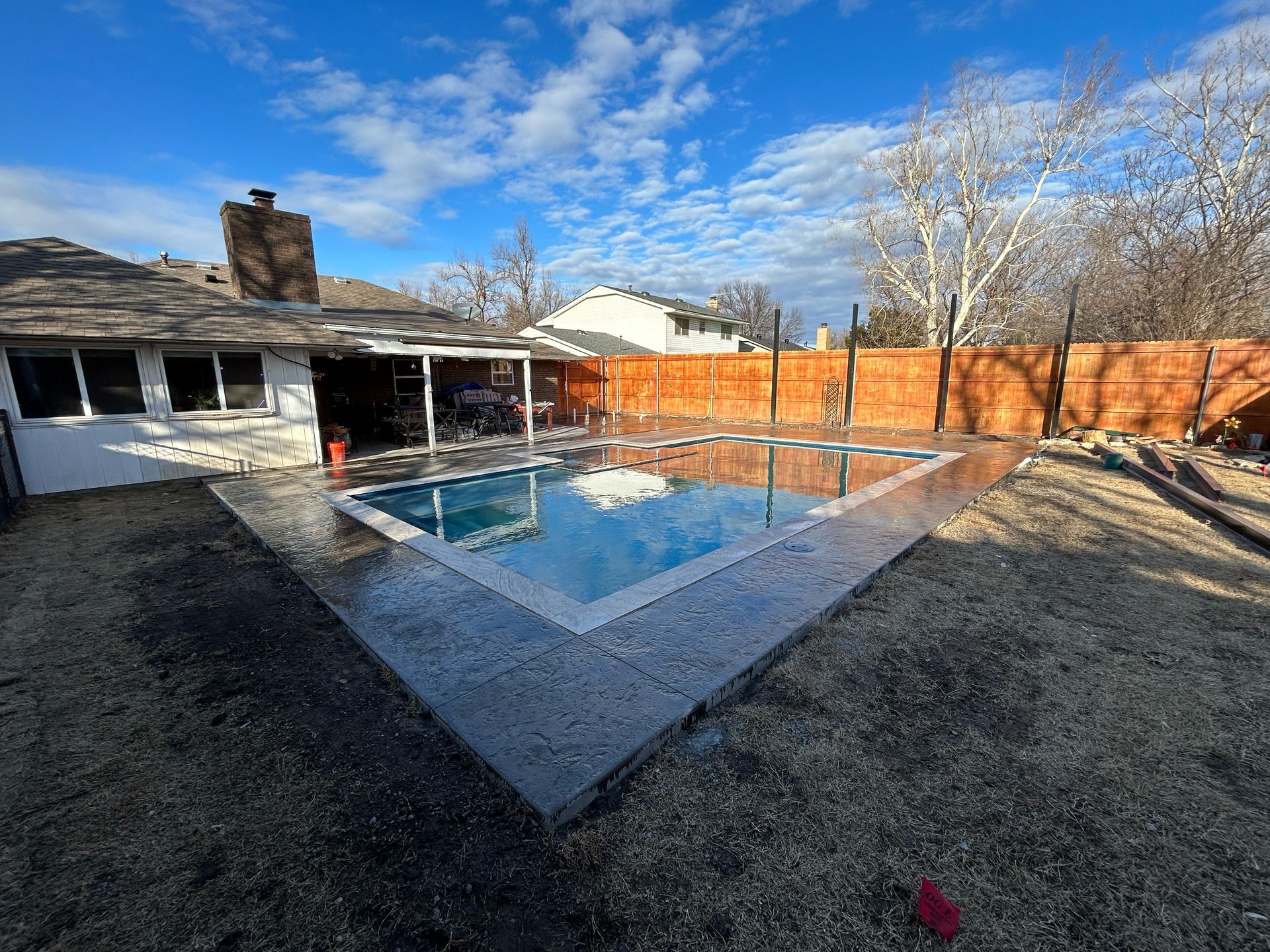 A large swimming pool is in the backyard of a house.