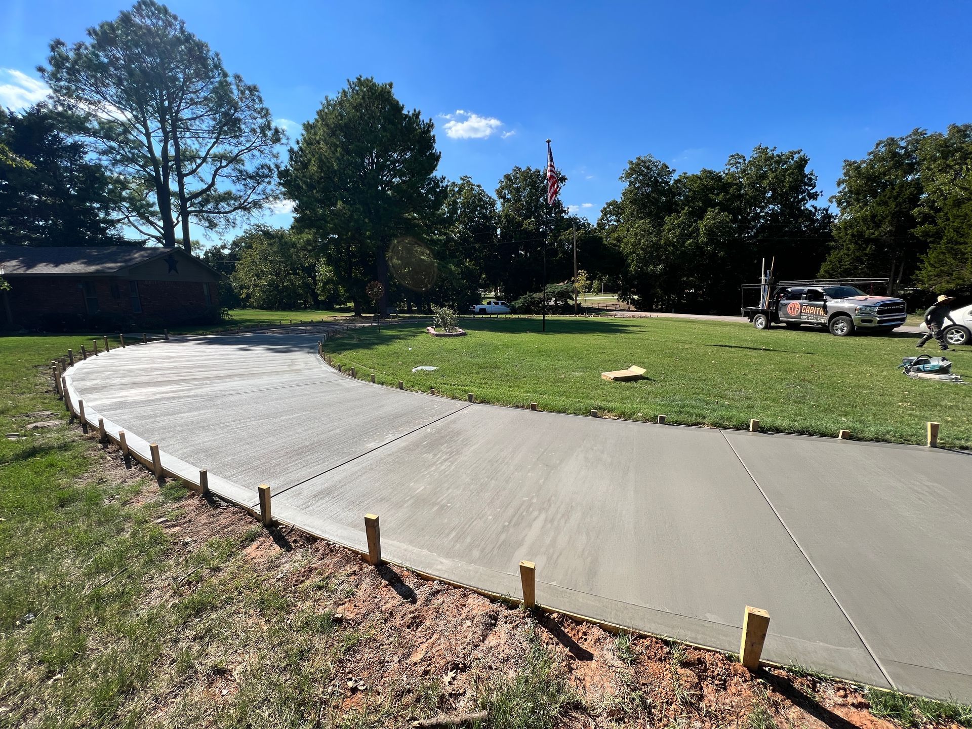 A concrete driveway is being built in the middle of a grassy field.