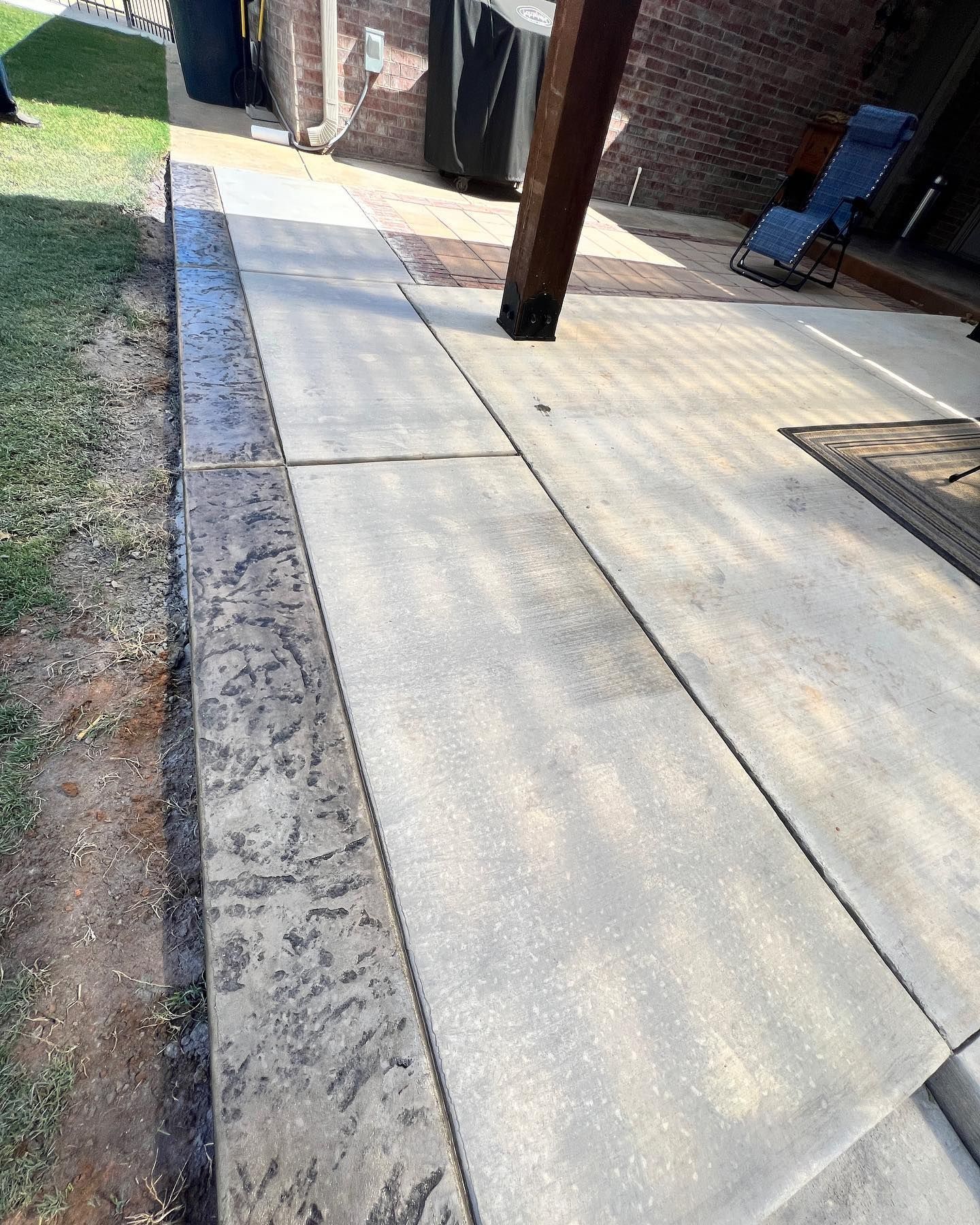 A patio with a chair and a brick wall in the background.