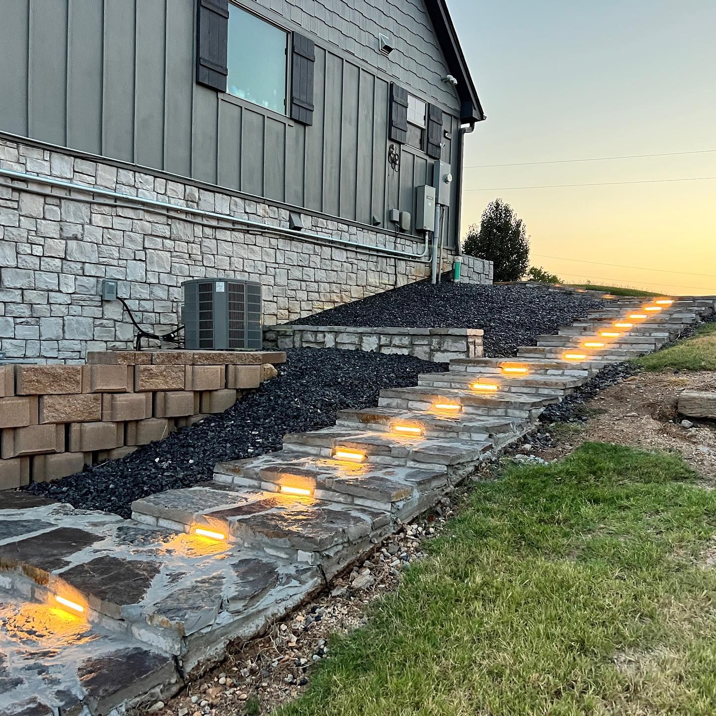 A stone walkway with lights on the side of a house.