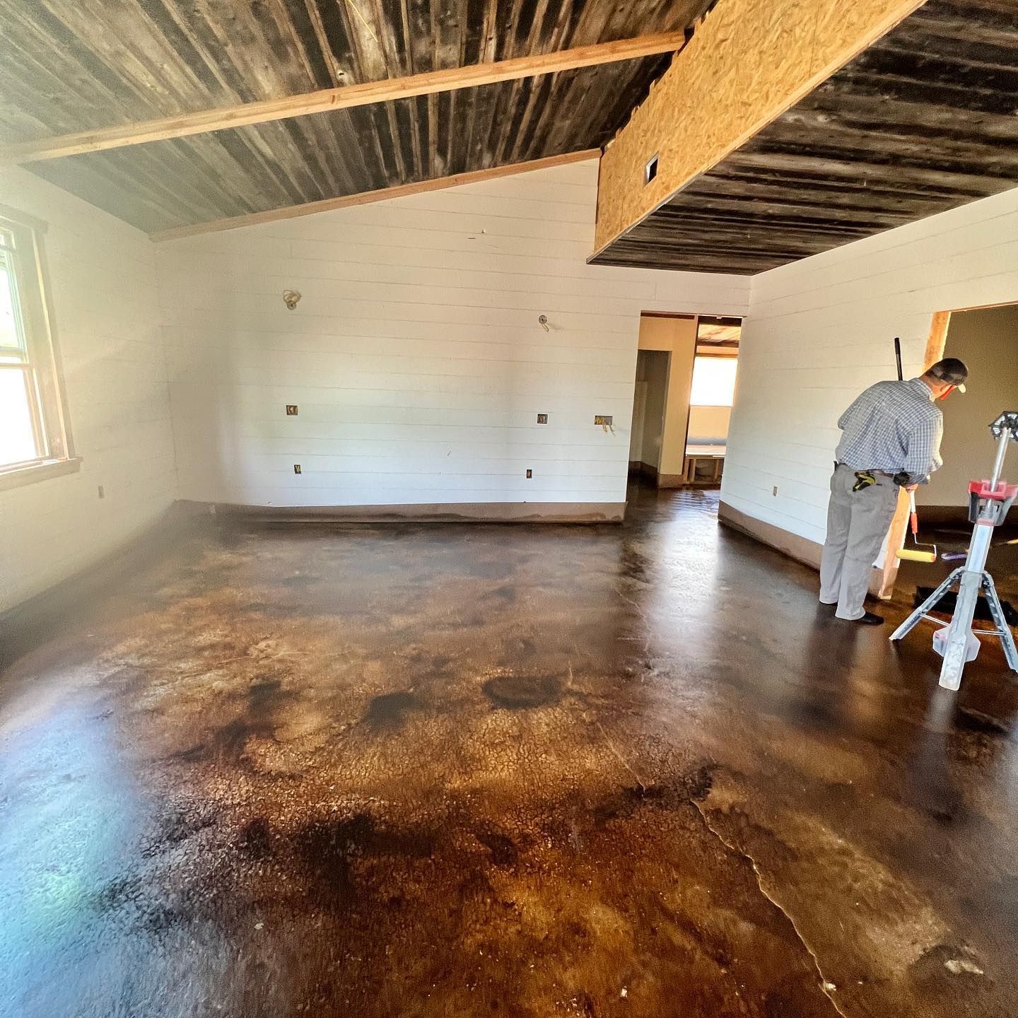 A man is standing in an empty room with a wooden ceiling