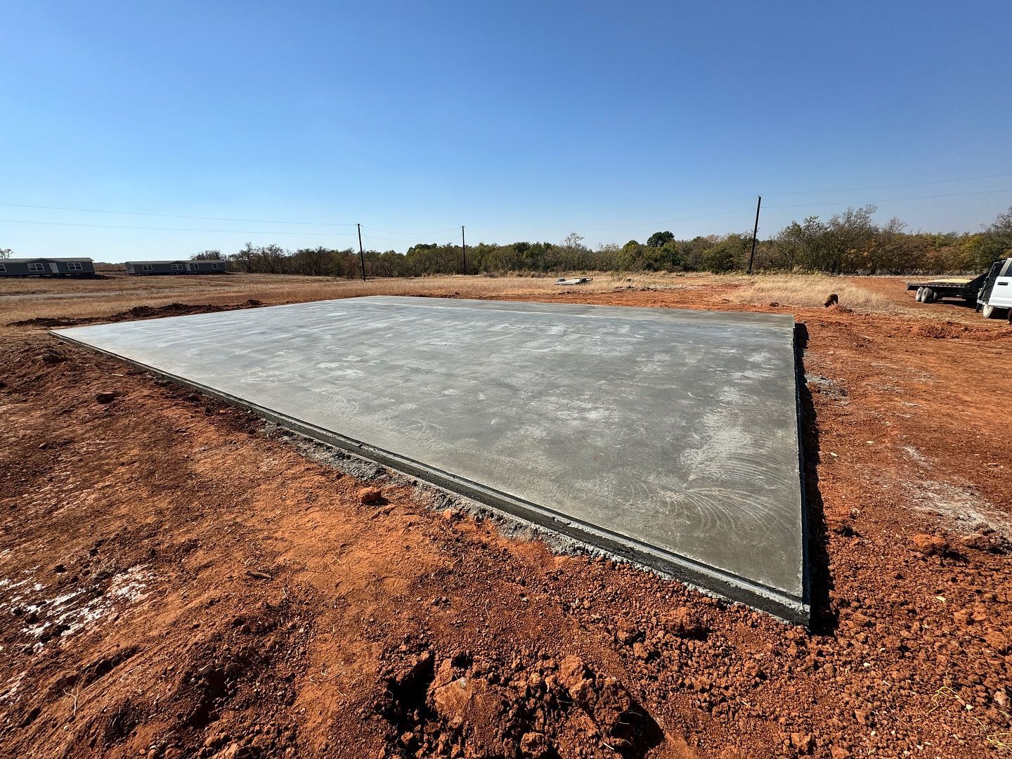A large concrete slab is sitting in the middle of a dirt field.
