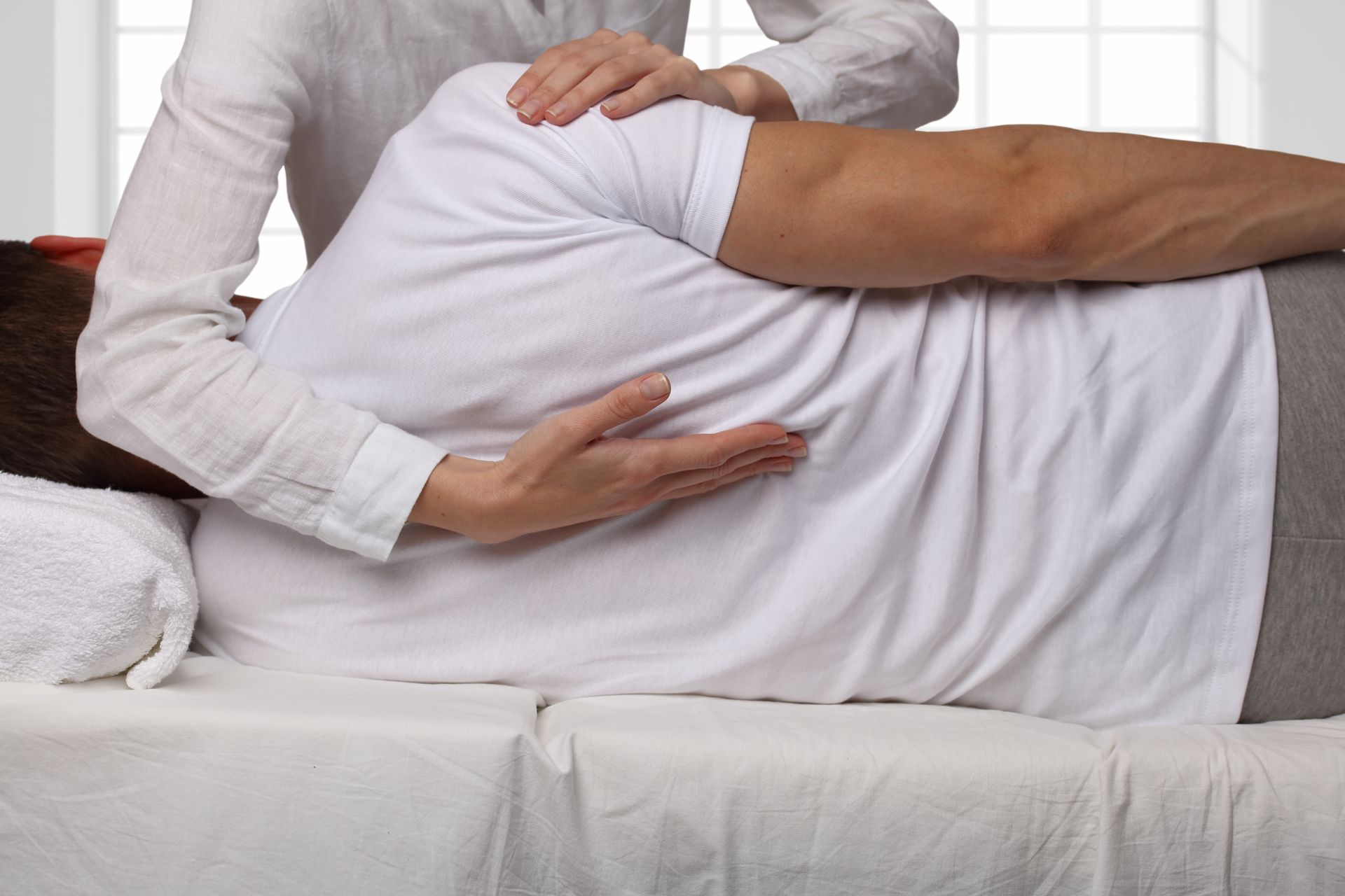 A woman is giving a man a massage on a bed.