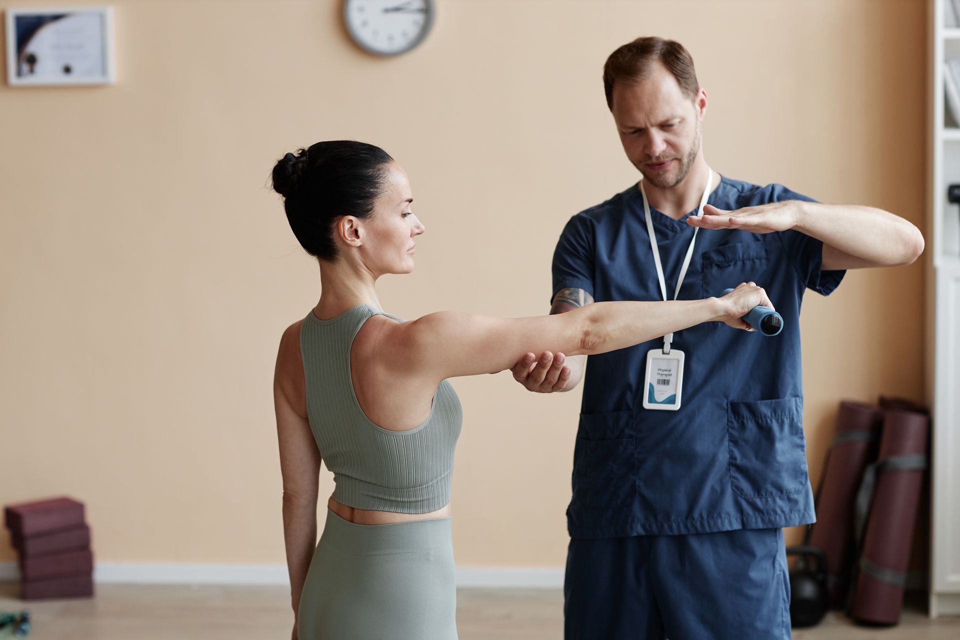 A man is examining a woman 's arm in a gym.