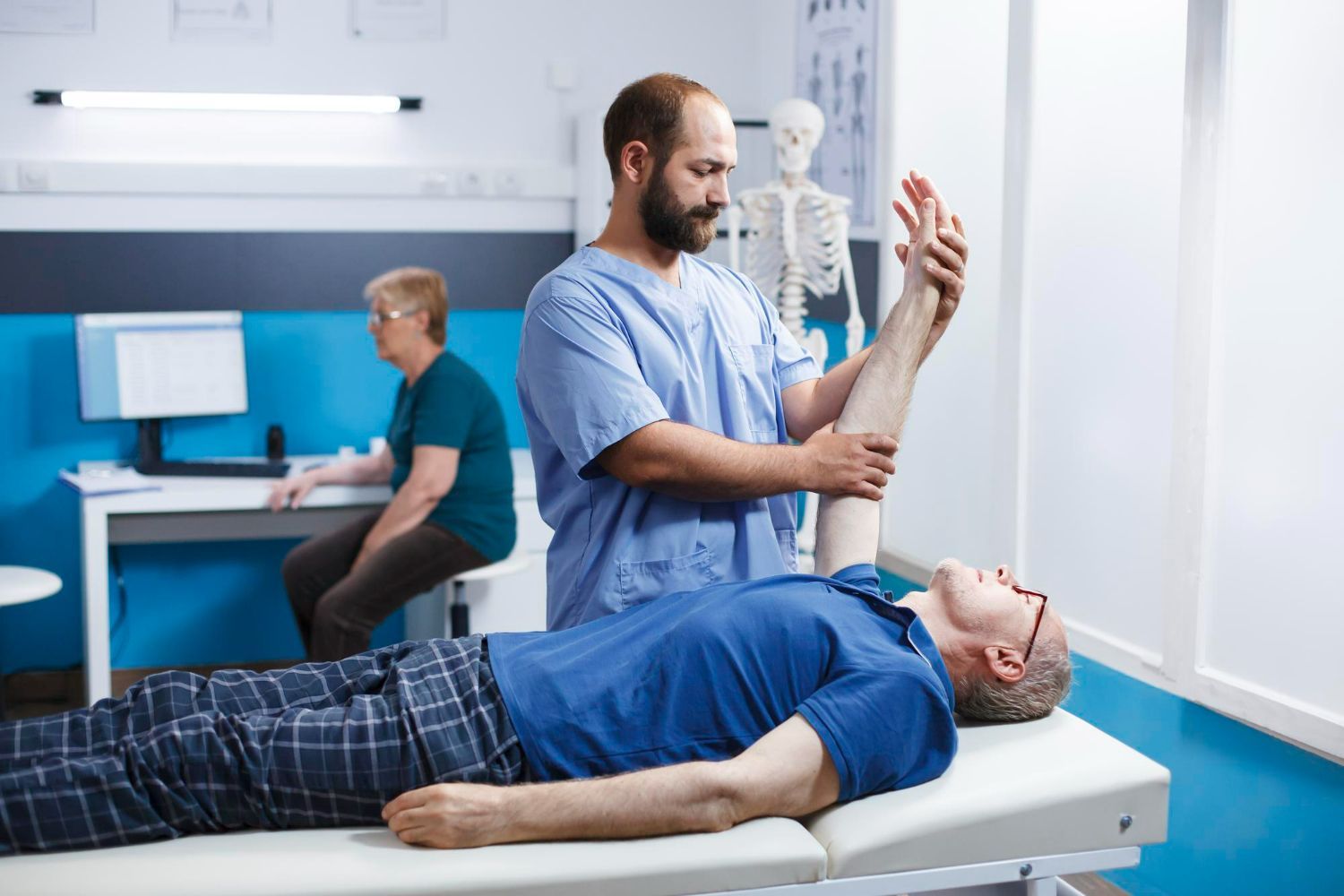 A man is laying on a bed while a doctor examines his arm.
