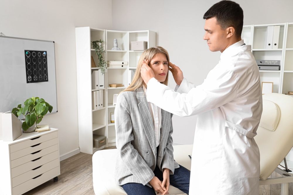 A doctor is examining a woman 's ear in an office.