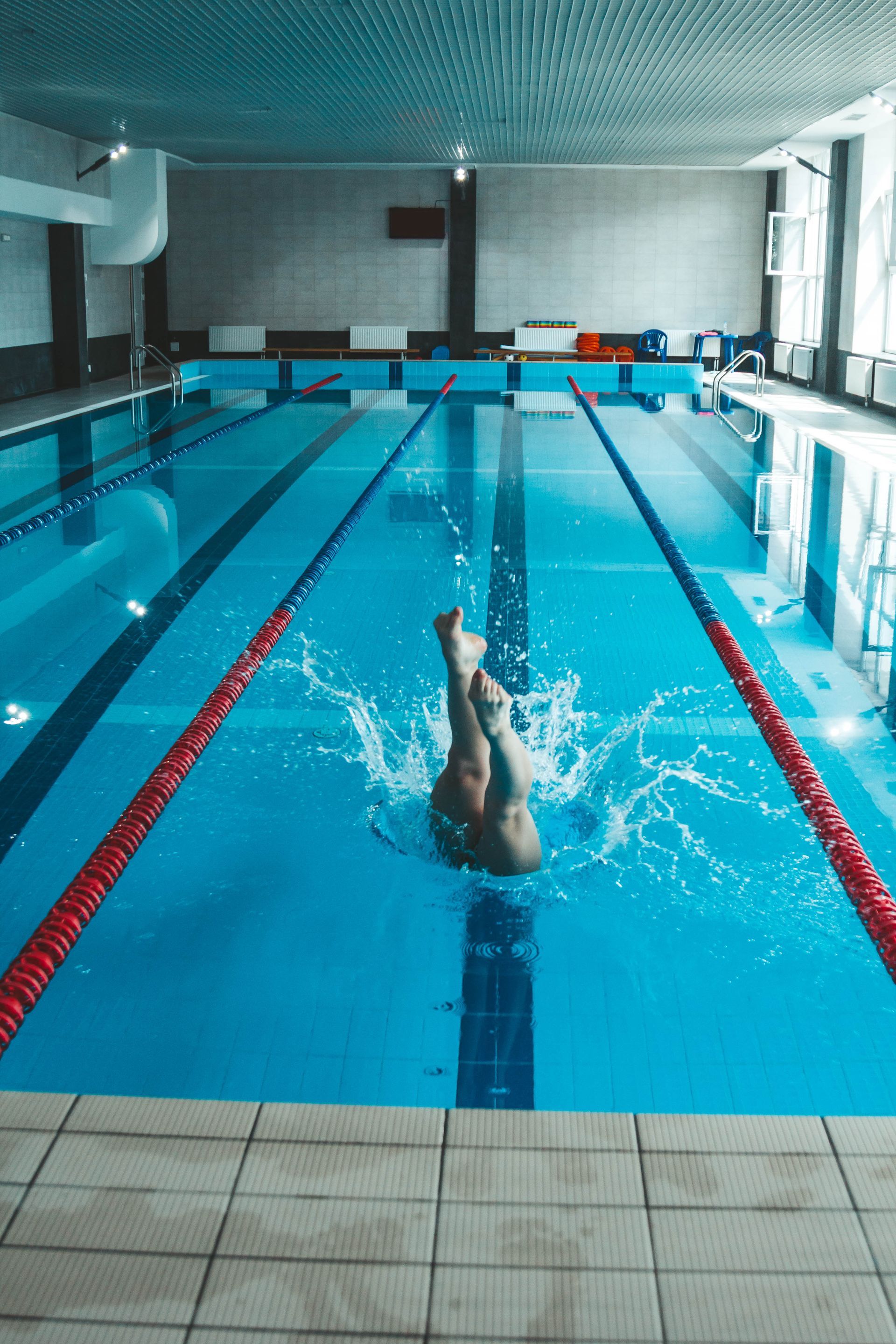 A man is diving into an indoor swimming pool.