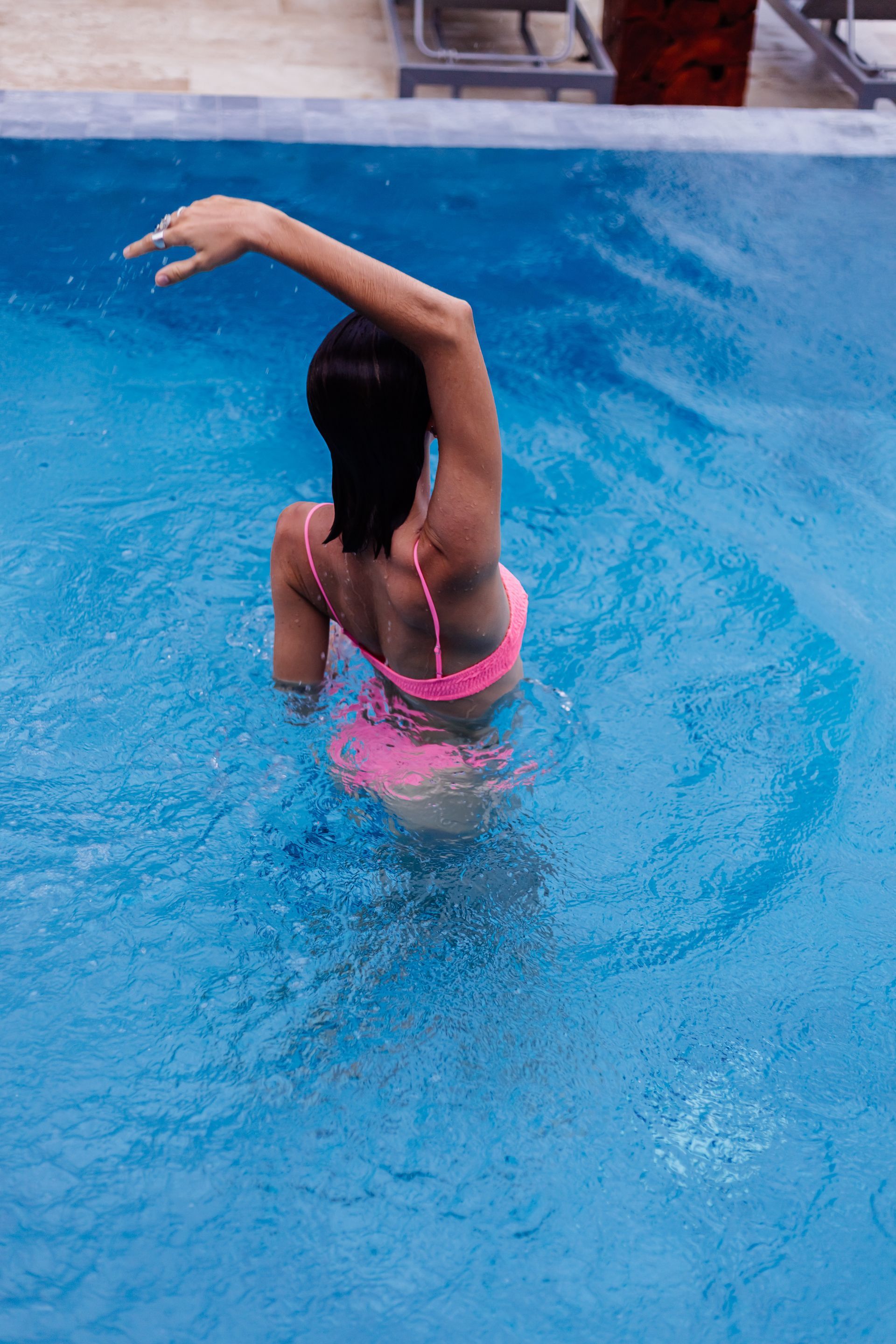 A woman in a pink bikini is standing in a swimming pool.