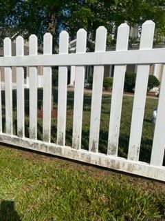 a white picket fence is sitting in the grass in front of a house .