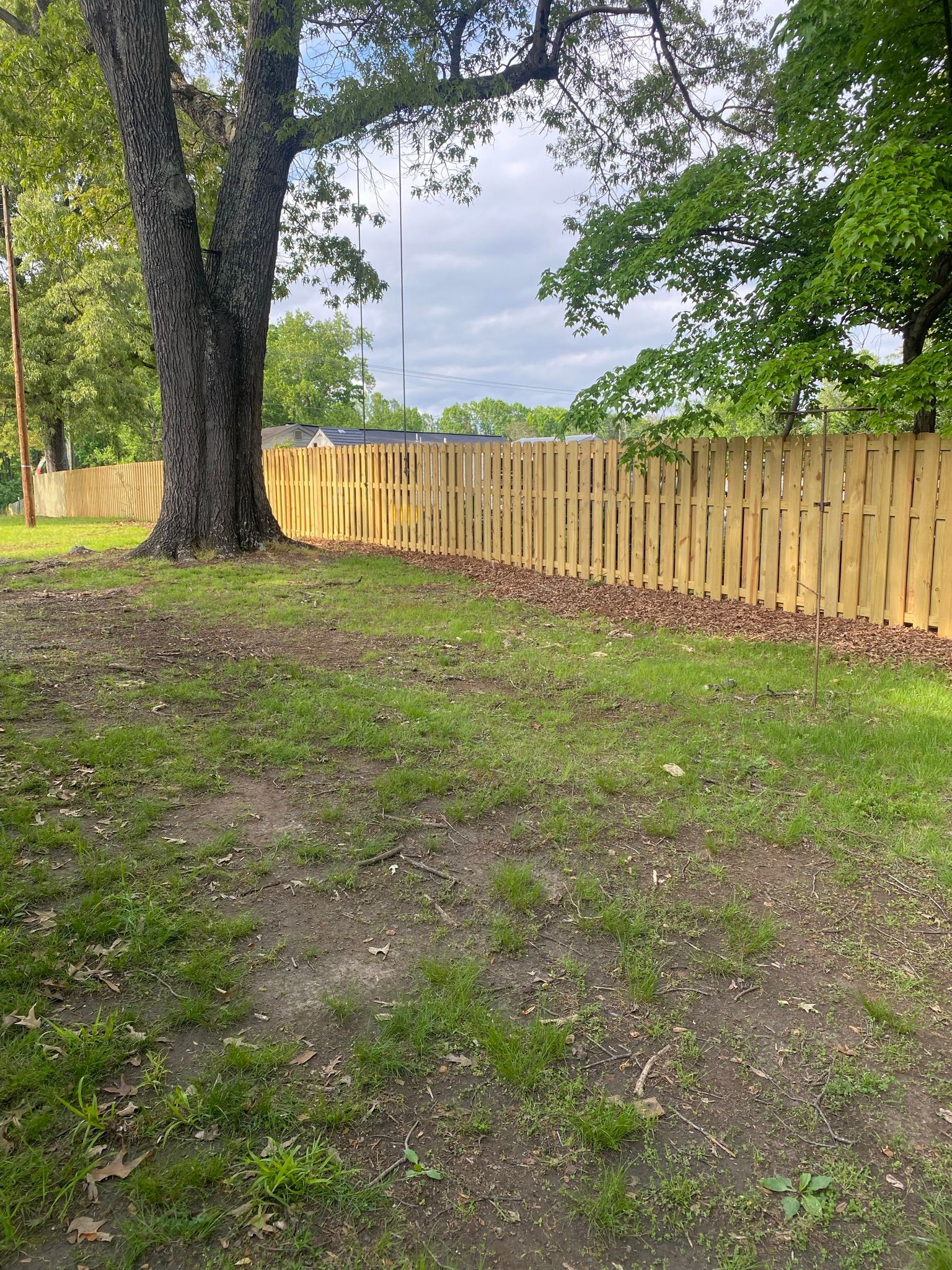 a wooden fence is surrounded by trees in a yard .