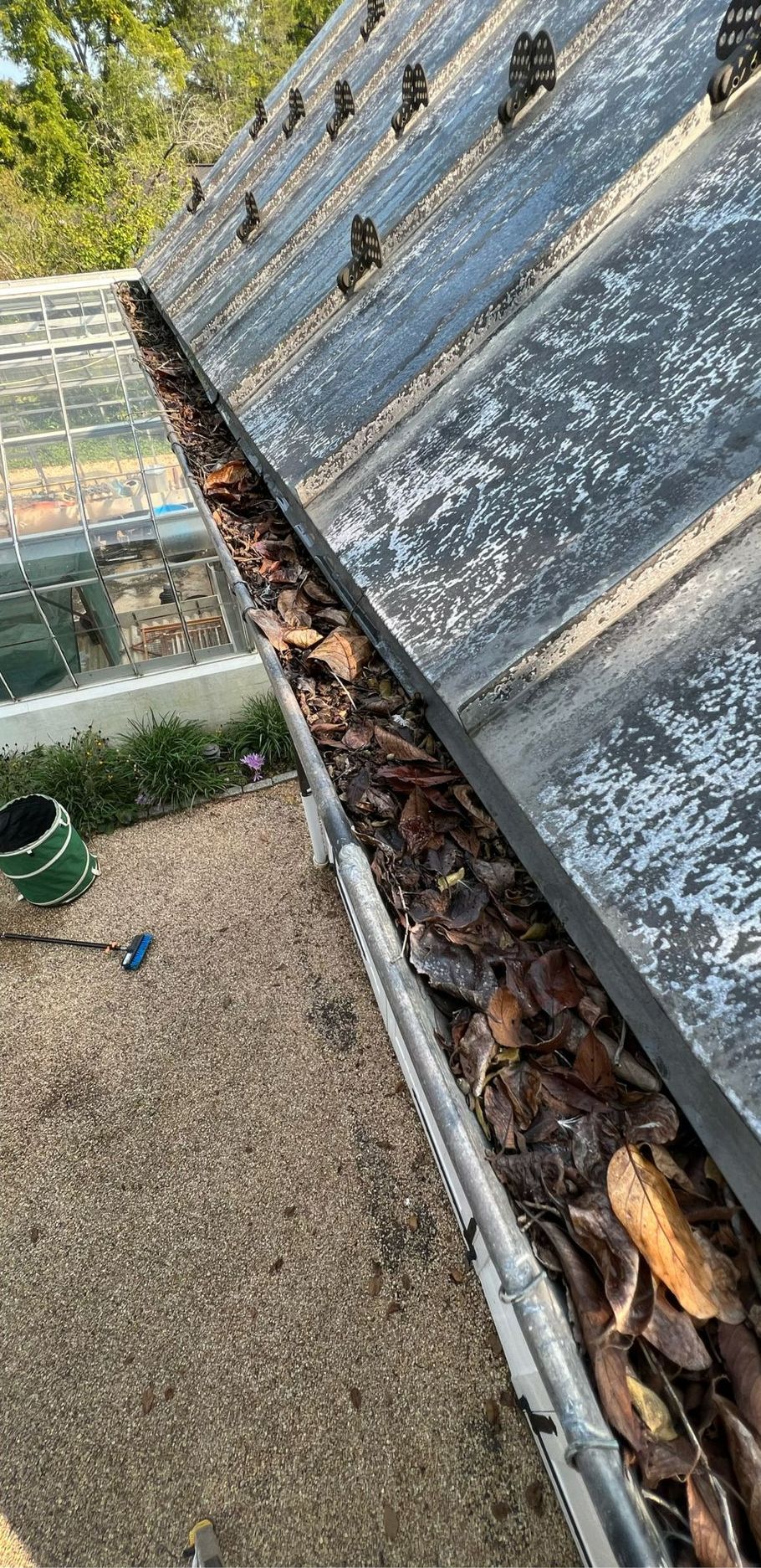 a gutter filled with leaves on the side of a roof .