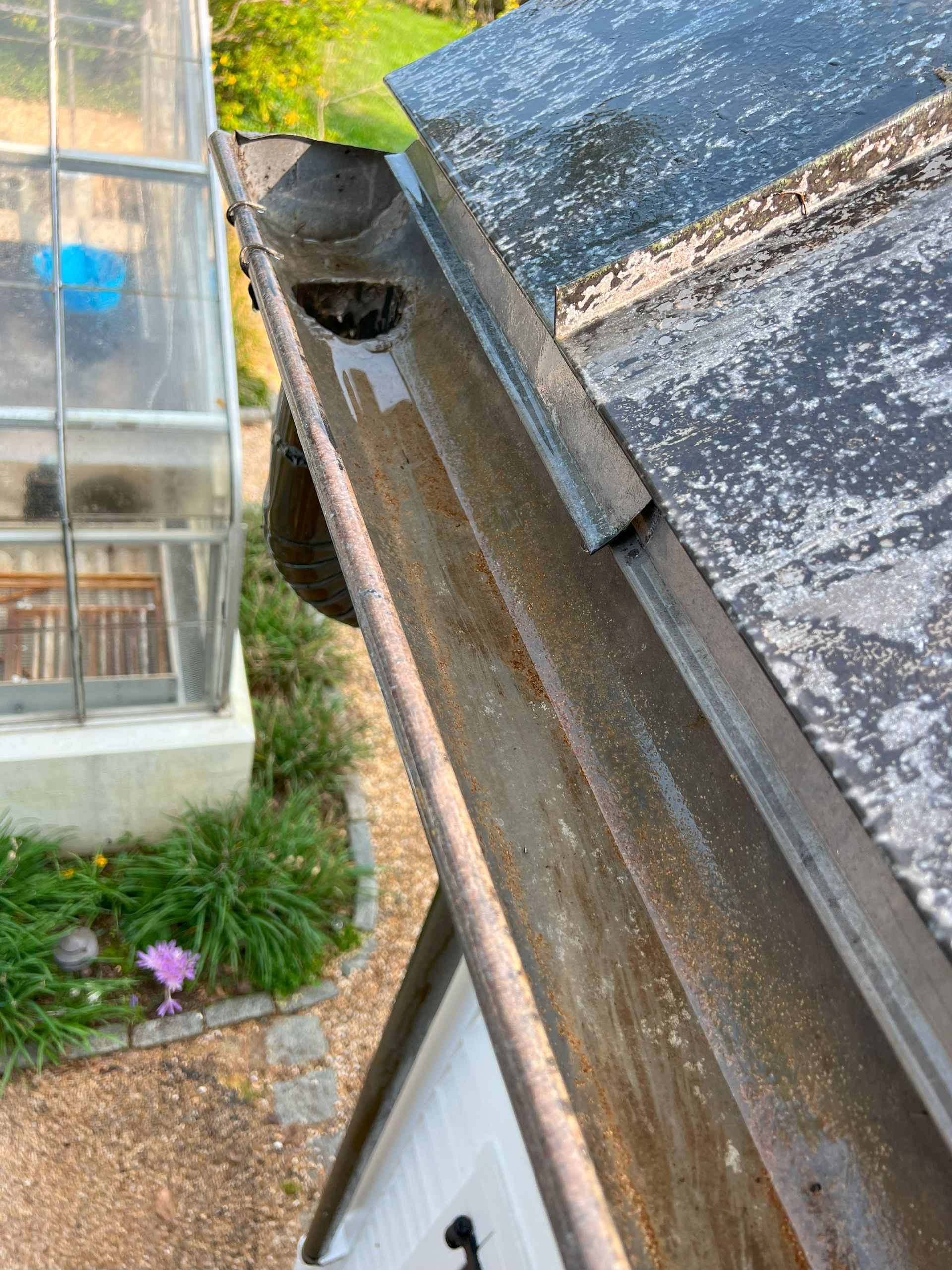 a close up of a gutter on a roof next to a greenhouse .
