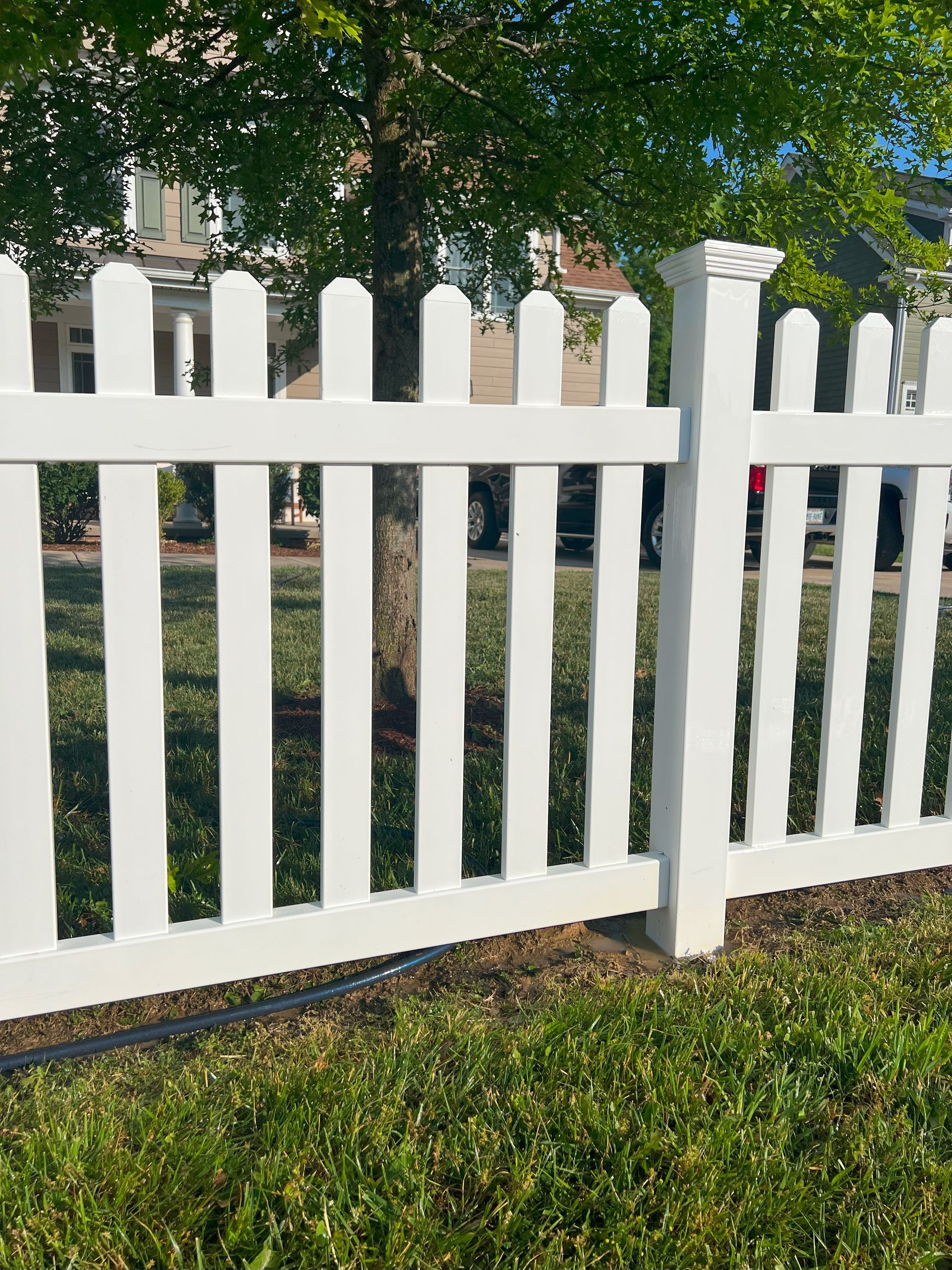 a white picket fence surrounds a lush green yard .