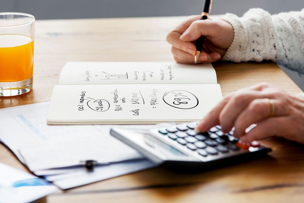 A person is using a calculator and writing in a notebook.